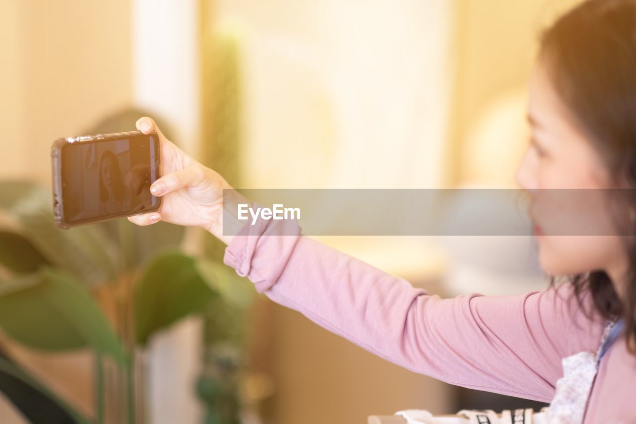 Young woman photographing with mobile phone at home