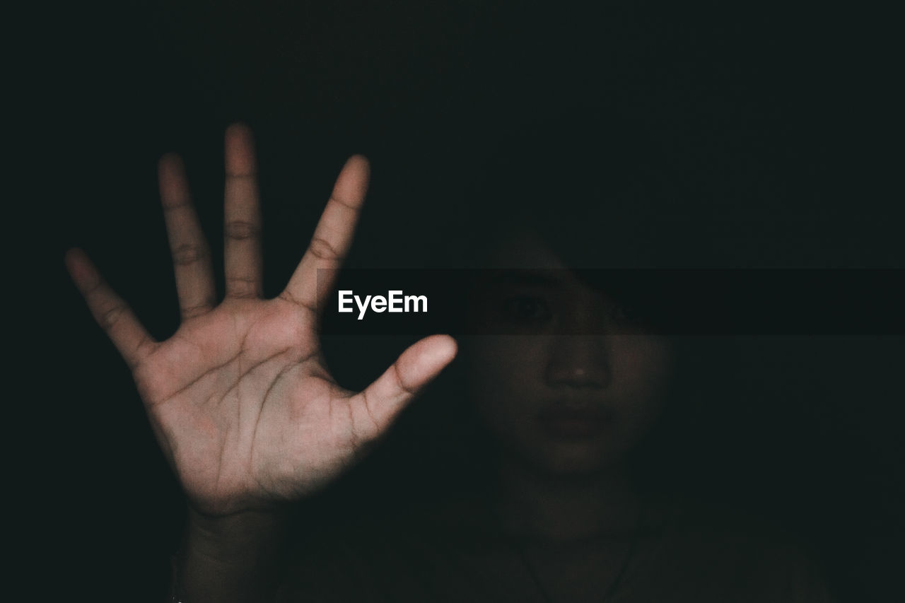 Portrait of young woman gesturing against black background