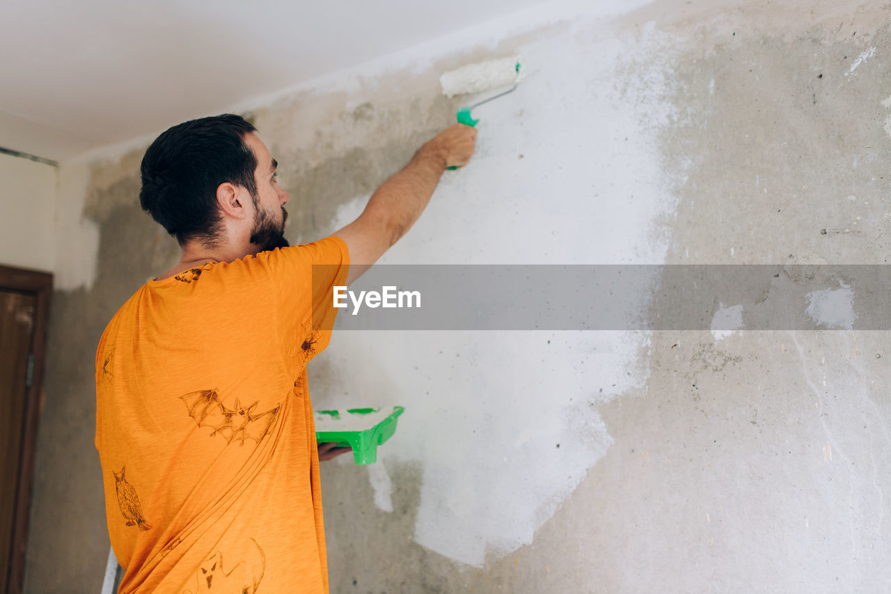 Rear view of man painting wall