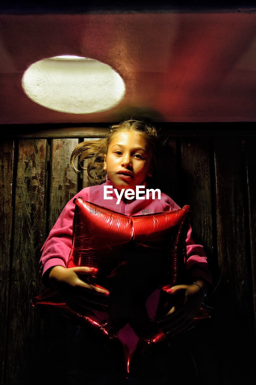 Portrait of cute girl with pillow lying on wooden floor