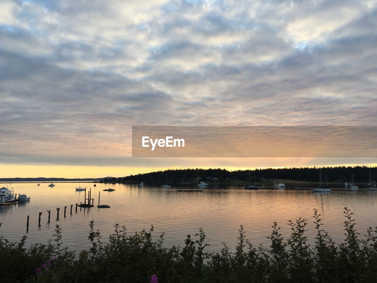 Scenic view of lake against cloudy sky during sunset