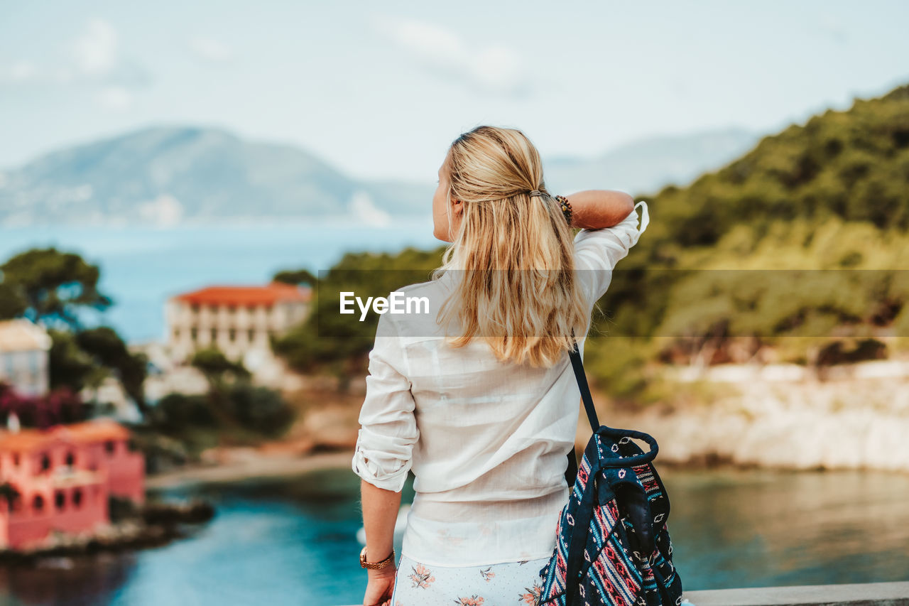 Rear view of woman standing by mountain against sky