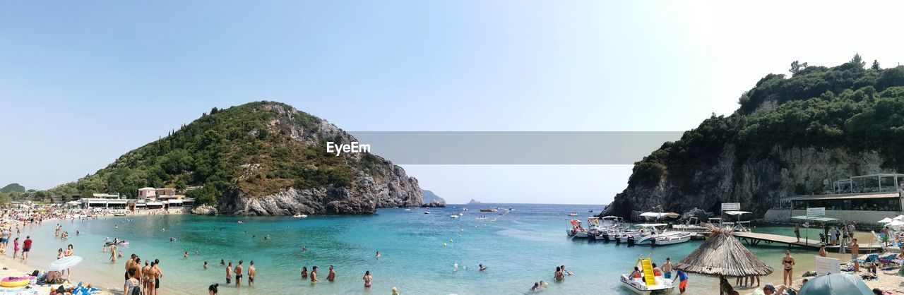 PANORAMIC VIEW OF PEOPLE ON BEACH AGAINST CLEAR SKY