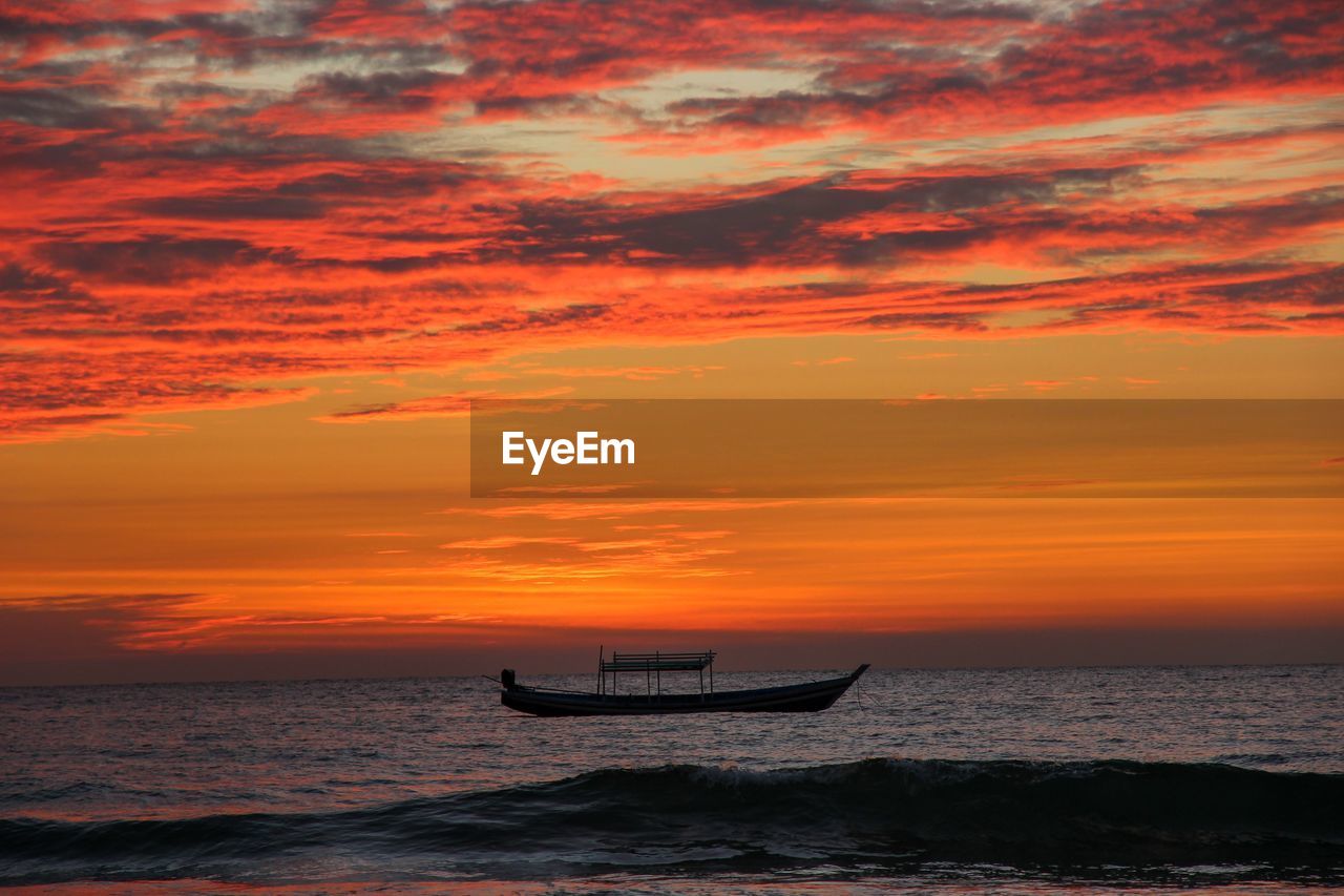 Silhouette boat in sea against orange sky