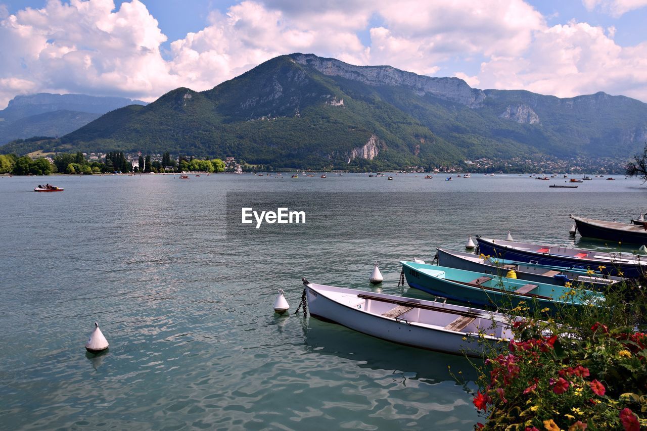 Sailboats moored in lake against sky