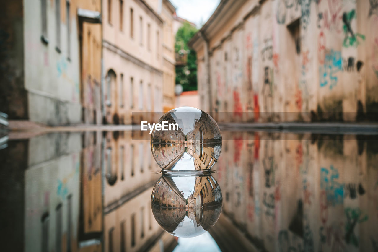 Close-up of crystal ball in puddle against building