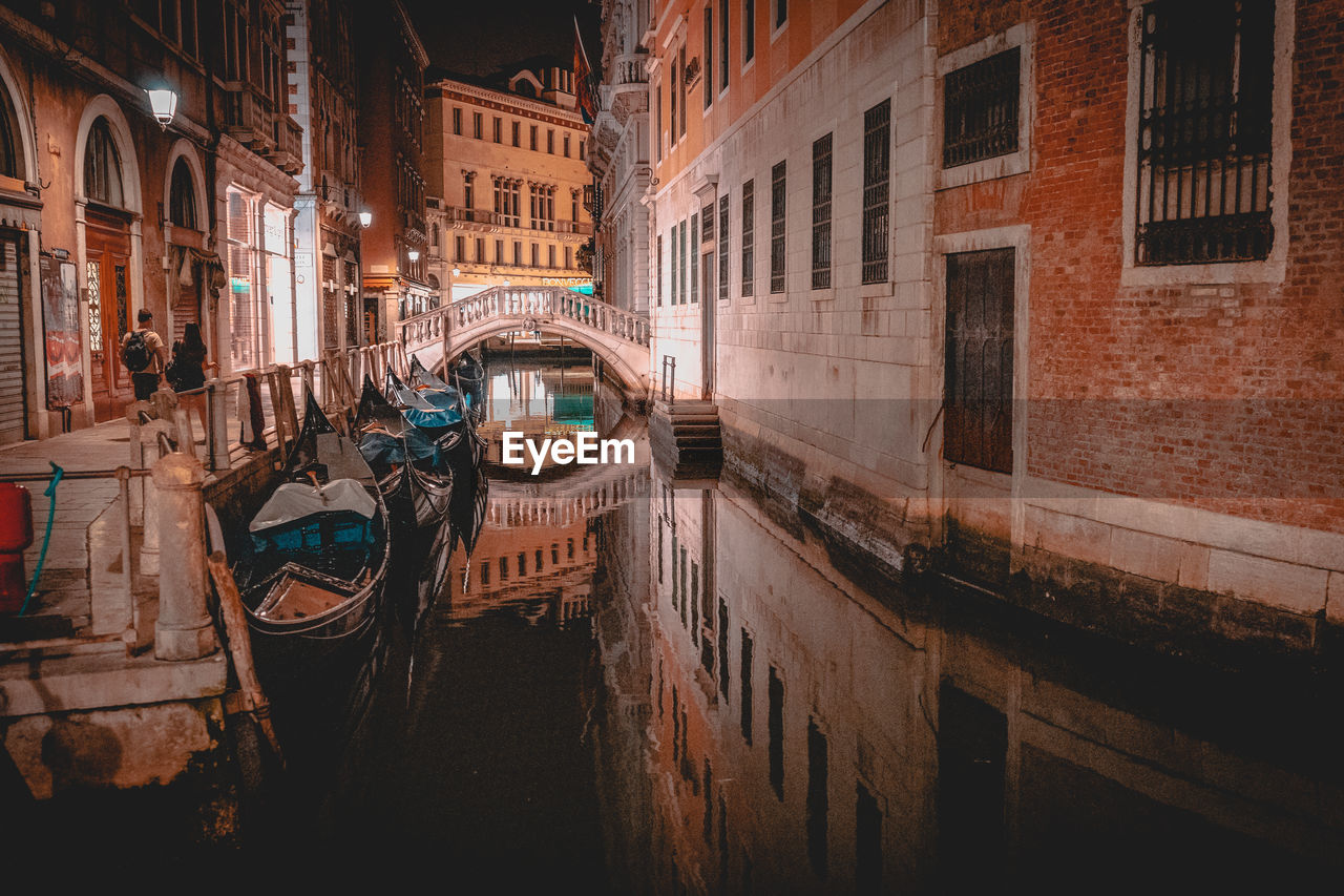 Canal amidst buildings in city at night