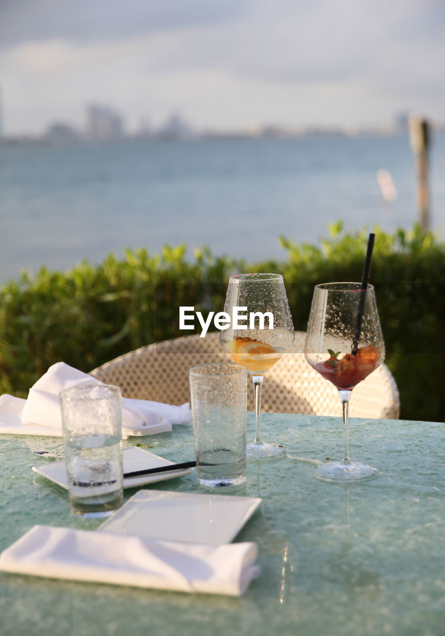 CLOSE-UP OF BEER ON TABLE AGAINST SWIMMING POOL