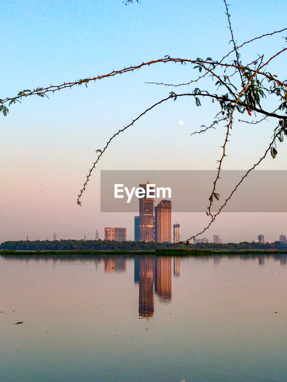 Scenic view of lake by buildings against sky during sunset