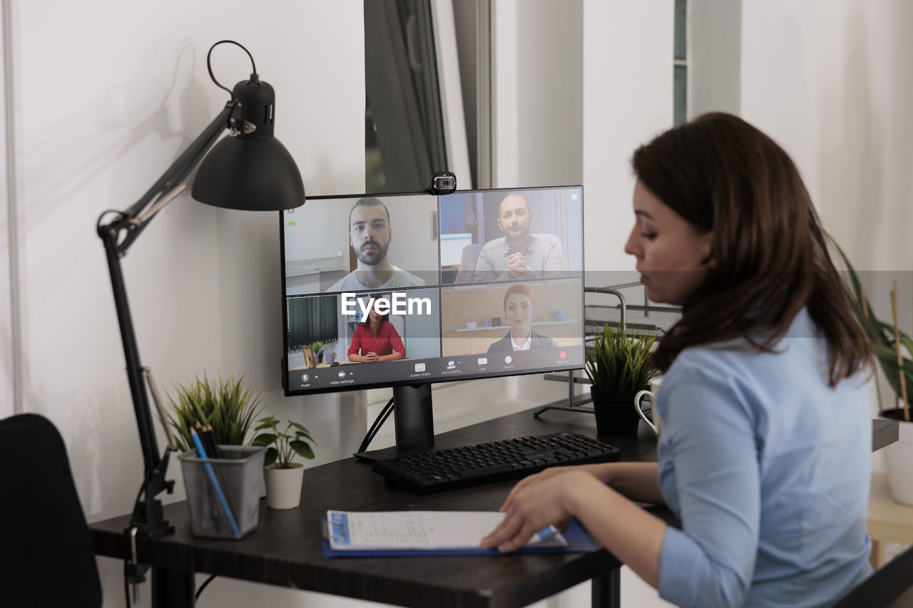 side view of young woman using laptop at desk in office