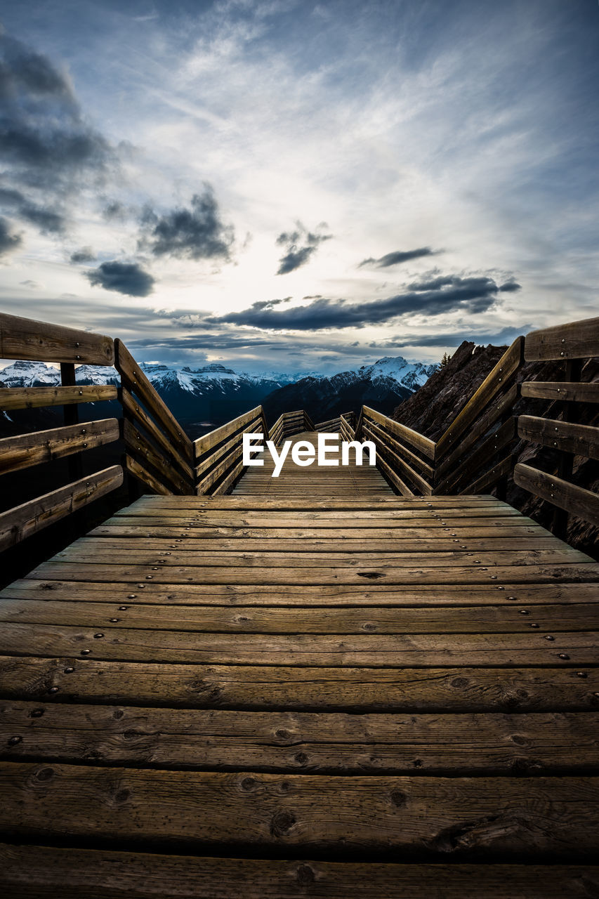 A wooden boardwalk on top of a mountain frames the surrounding skyline in banff, alberta, canada.