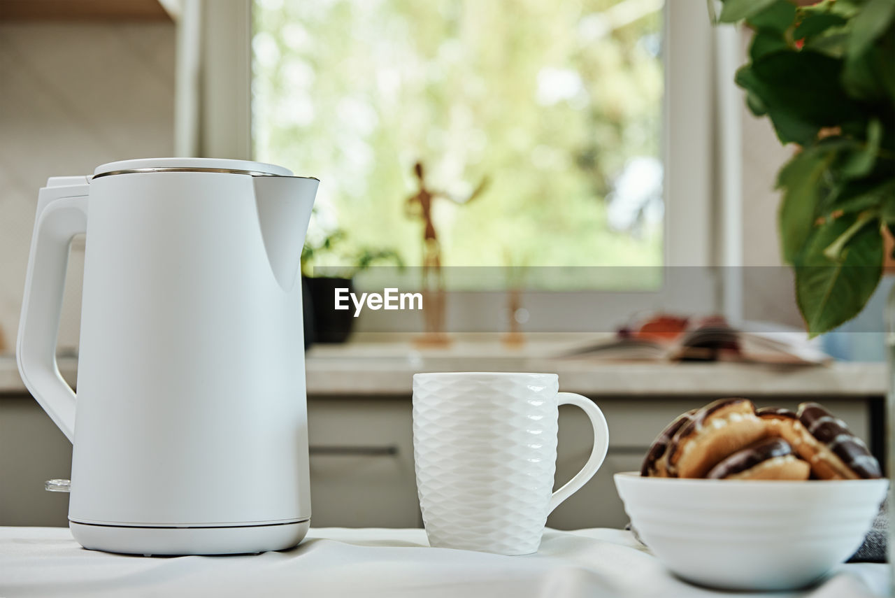 Electric kettle and cup for tea on table