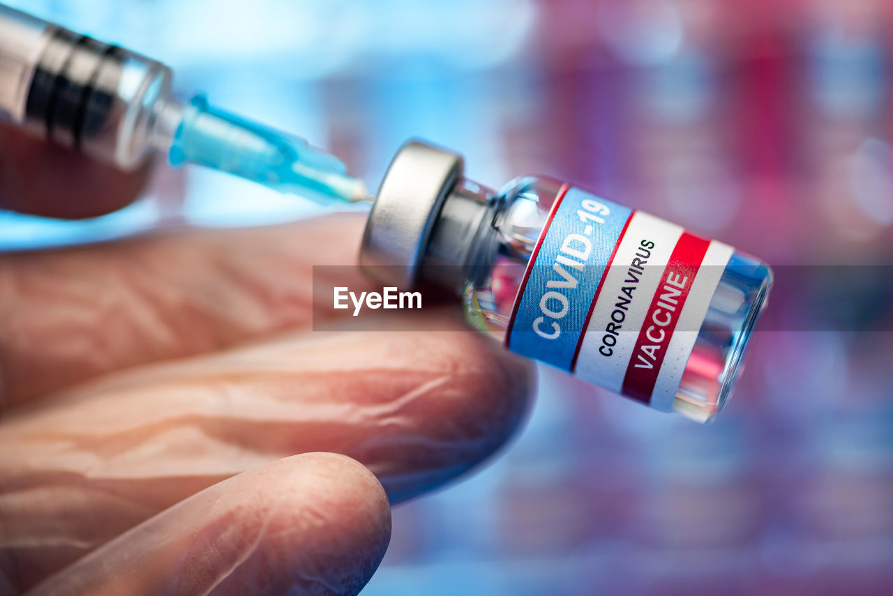 Close-up of medical person holding vials and syringe - covid 19 vaccine