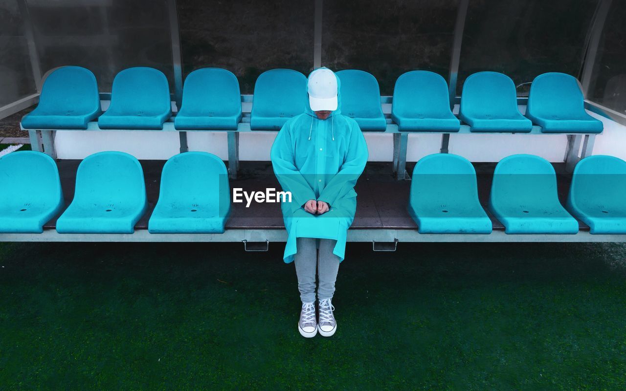 Woman in blue raincoat sitting on chair