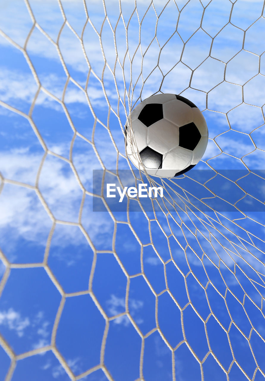 Soccer ball hitting in goal post against blue sky