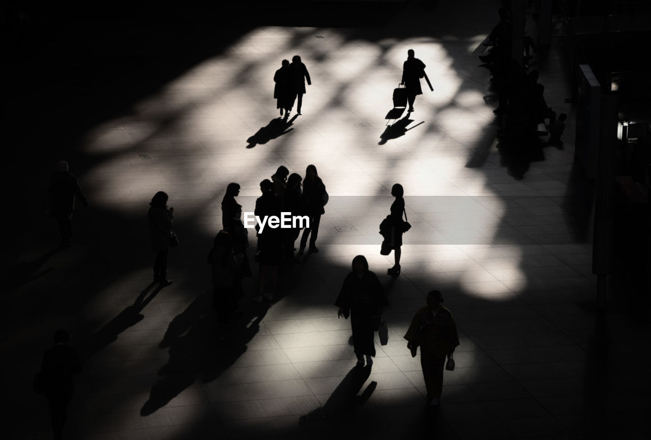 HIGH ANGLE VIEW OF SILHOUETTE PEOPLE WALKING ON STREET