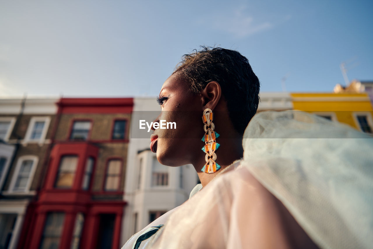 Portrait of woman looking away against colourful buildings