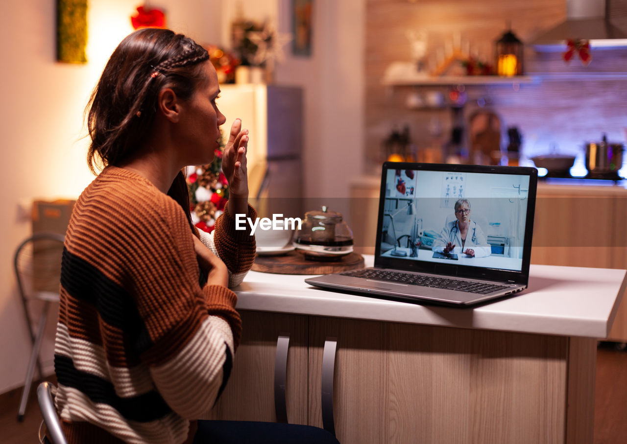 Woman using laptop on table at home