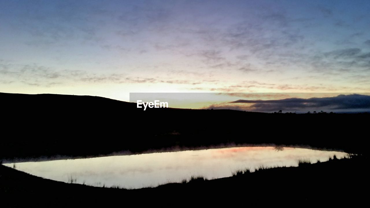SCENIC VIEW OF LAKE AGAINST SKY AT SUNSET
