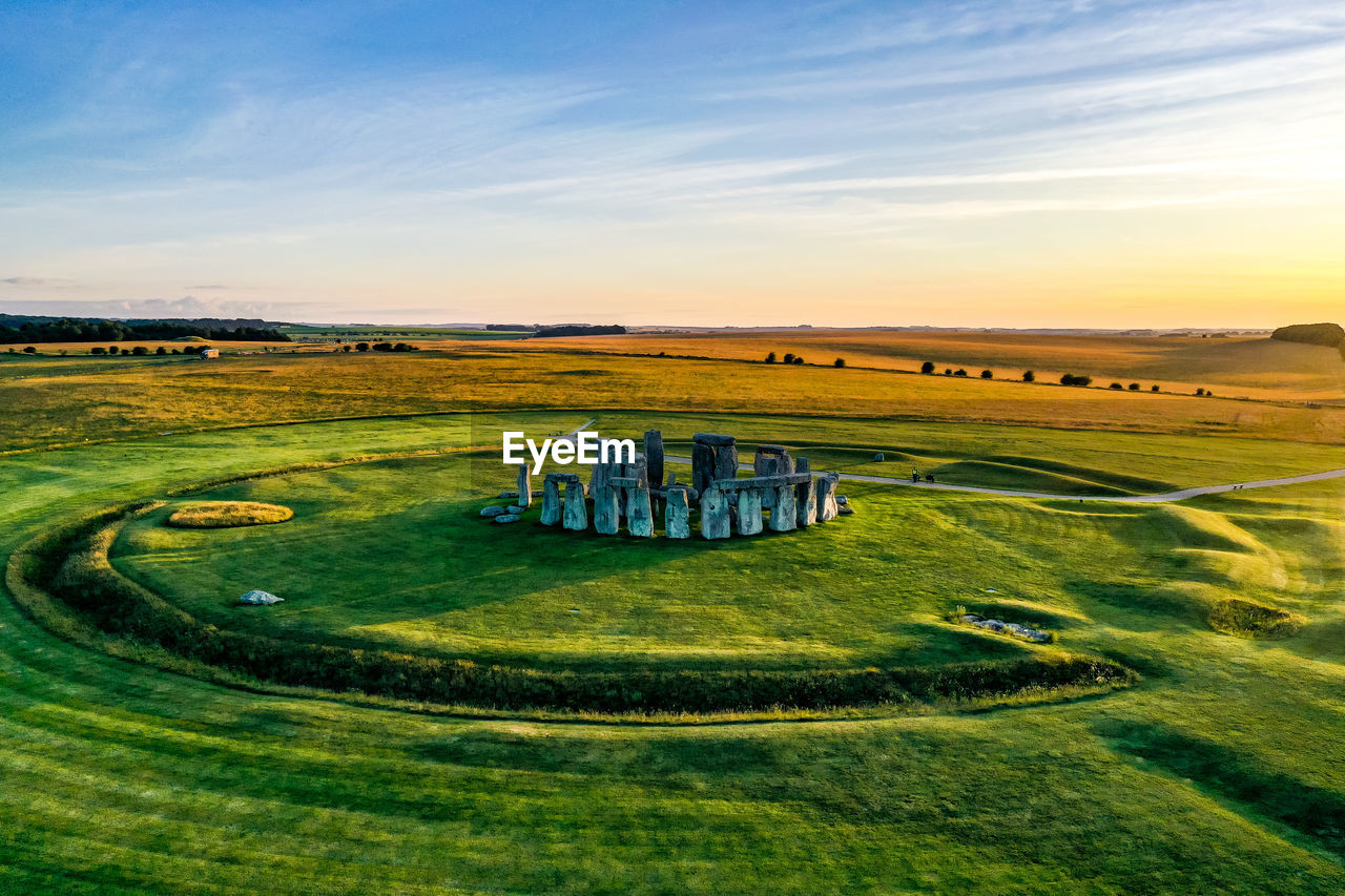 SCENIC VIEW OF GREEN LANDSCAPE AGAINST SKY DURING SUNSET