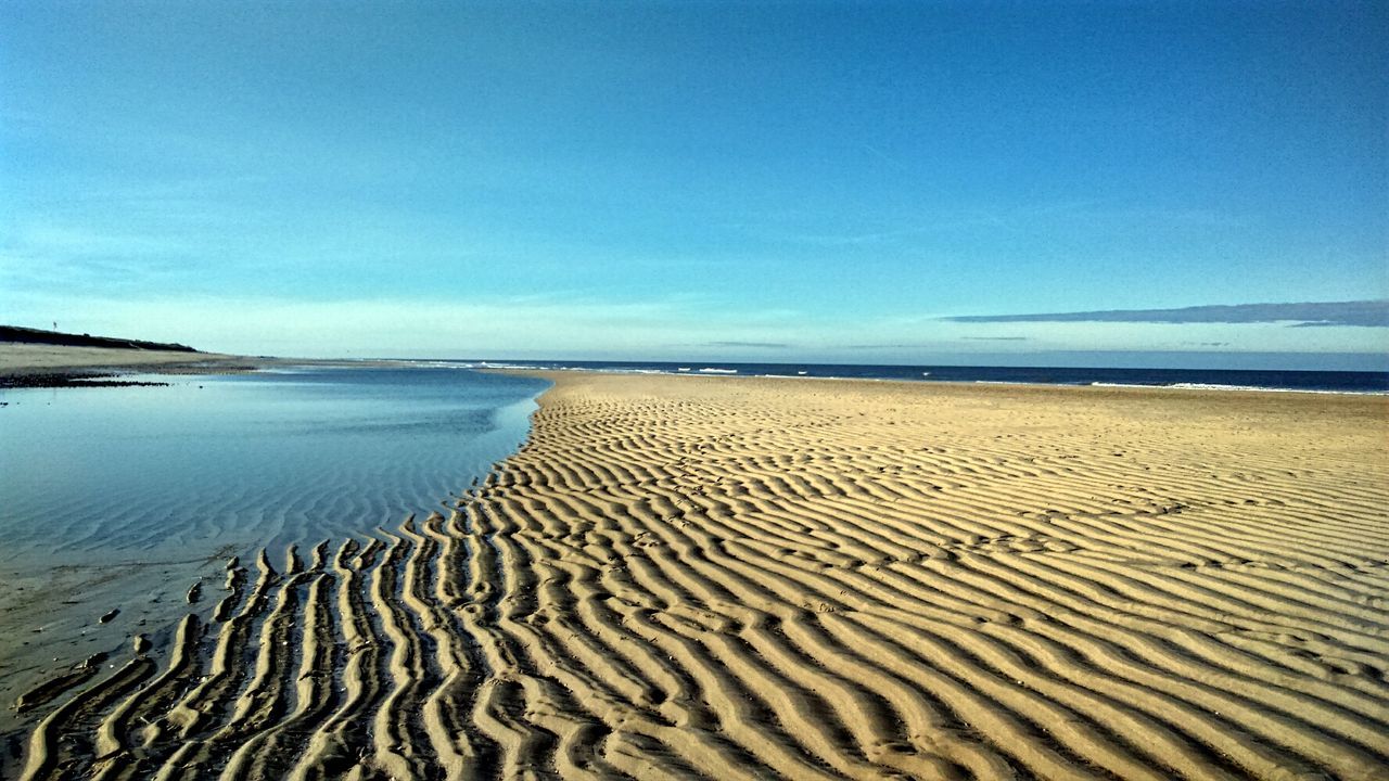 Scenic view of beach against blue sky