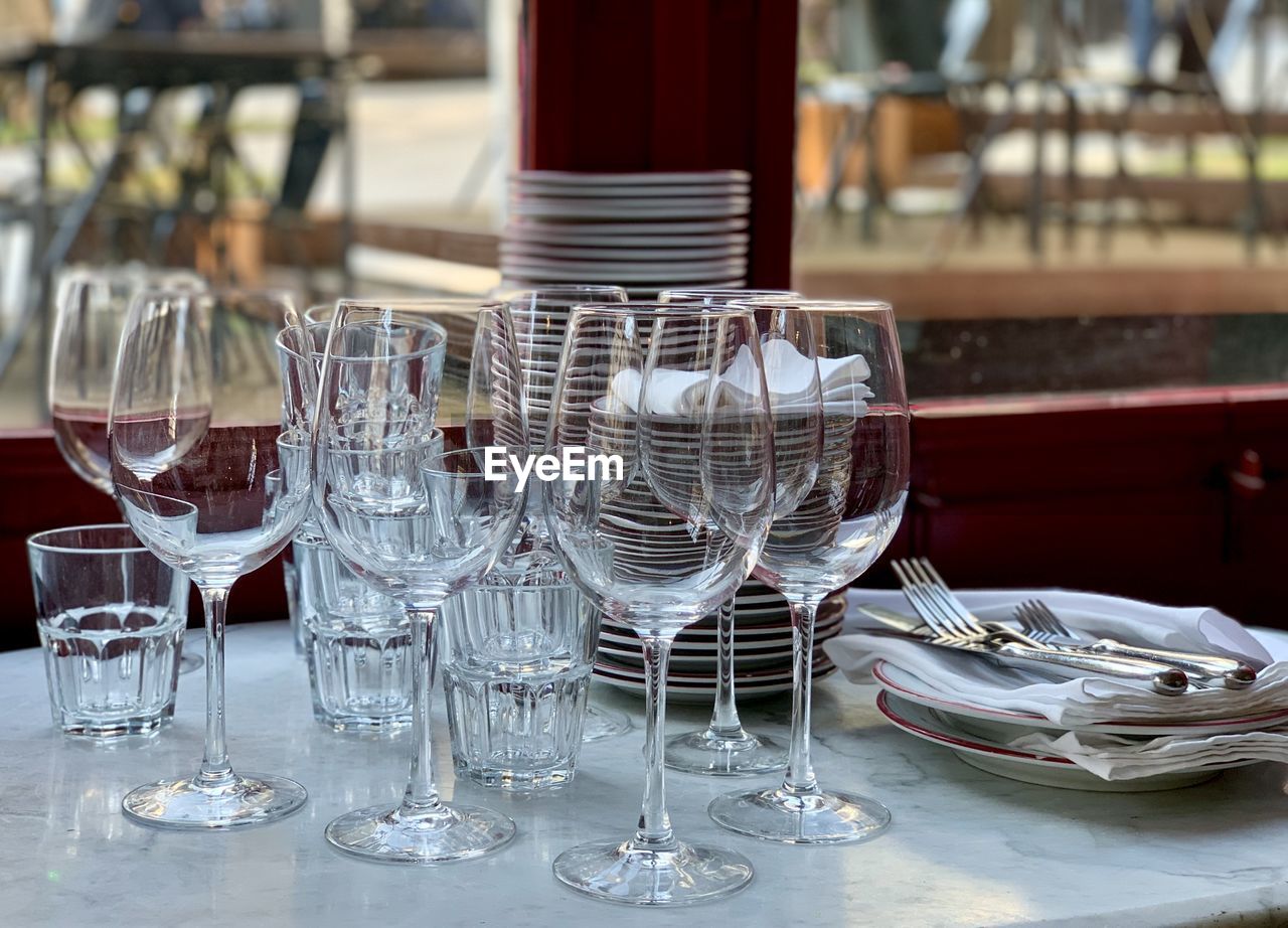 Glasses, plates and cutleries. clean wine and water glasses are on a marble table by the window