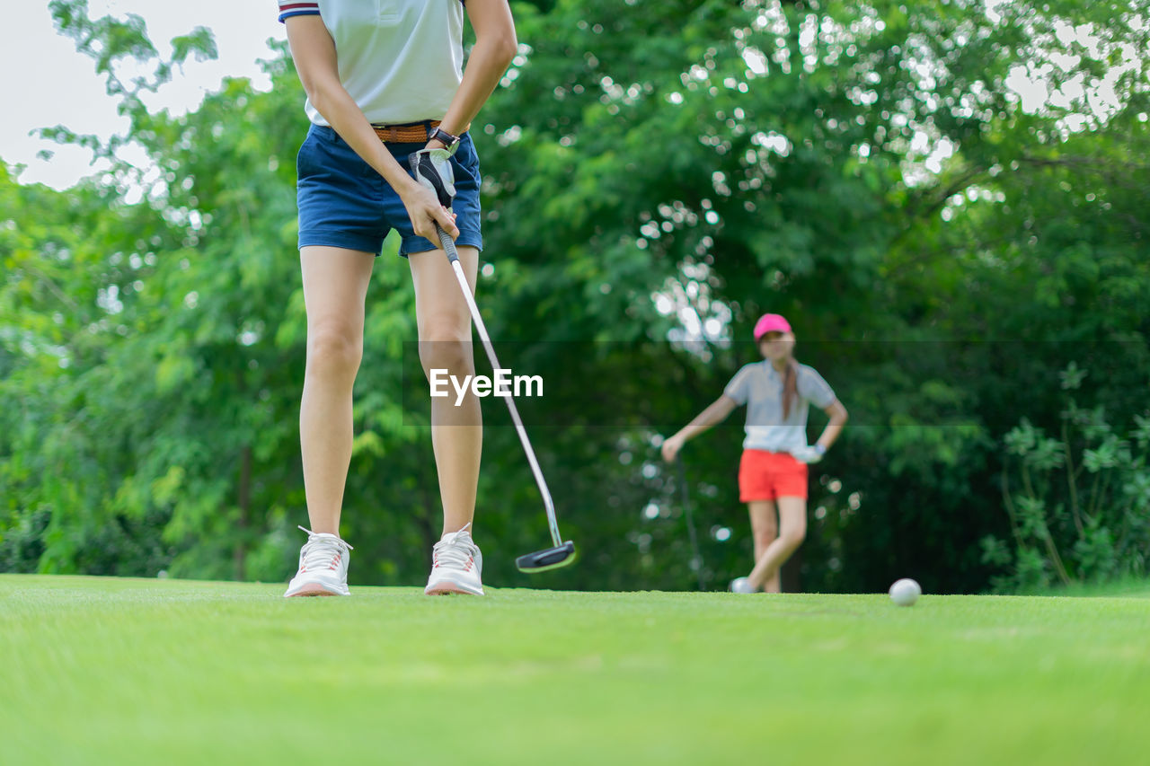 Low section of woman playing with golf with female friend in park