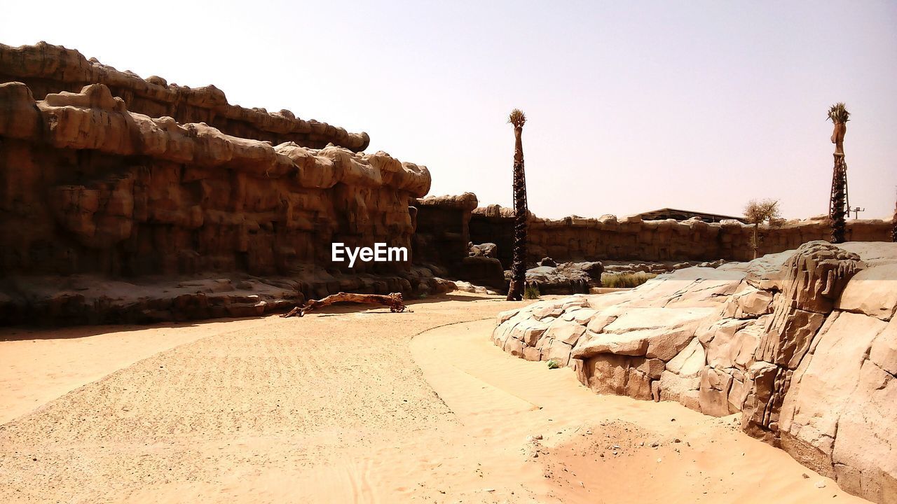 Walkway amidst rock formations against sky