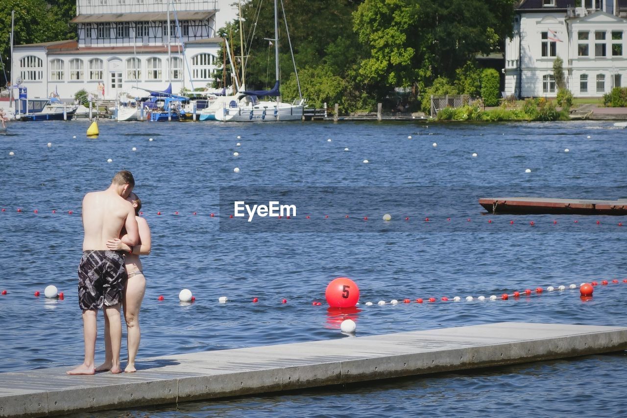 Couple kissing while standing on concrete pier in lake