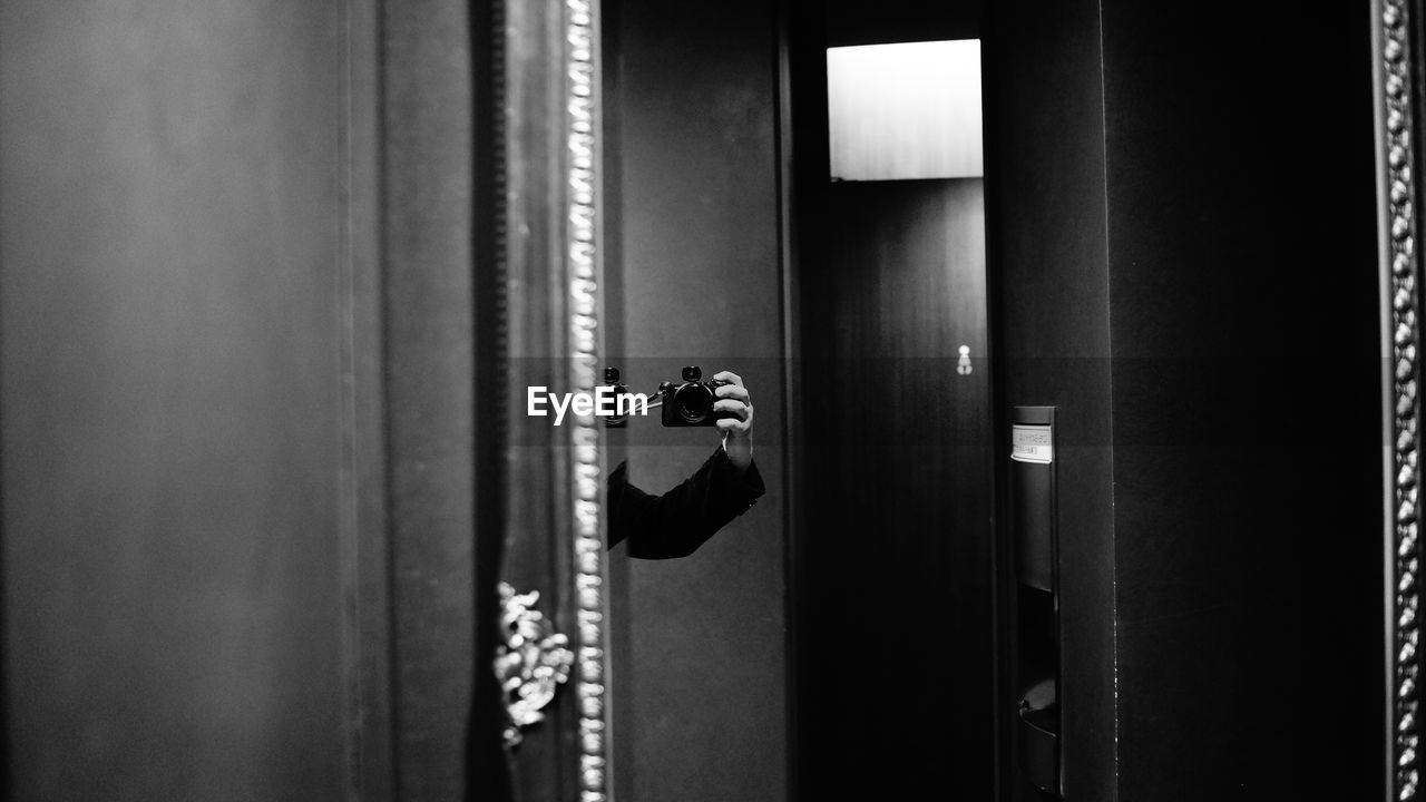 Cropped image of photographer photographing mirror at home