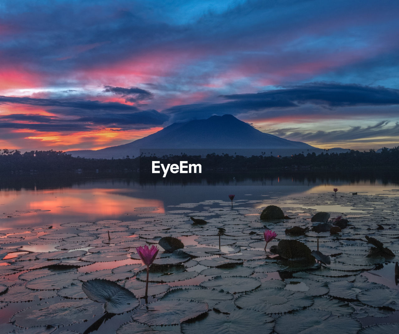 Scenic view of lake by mountains against sky during sunset