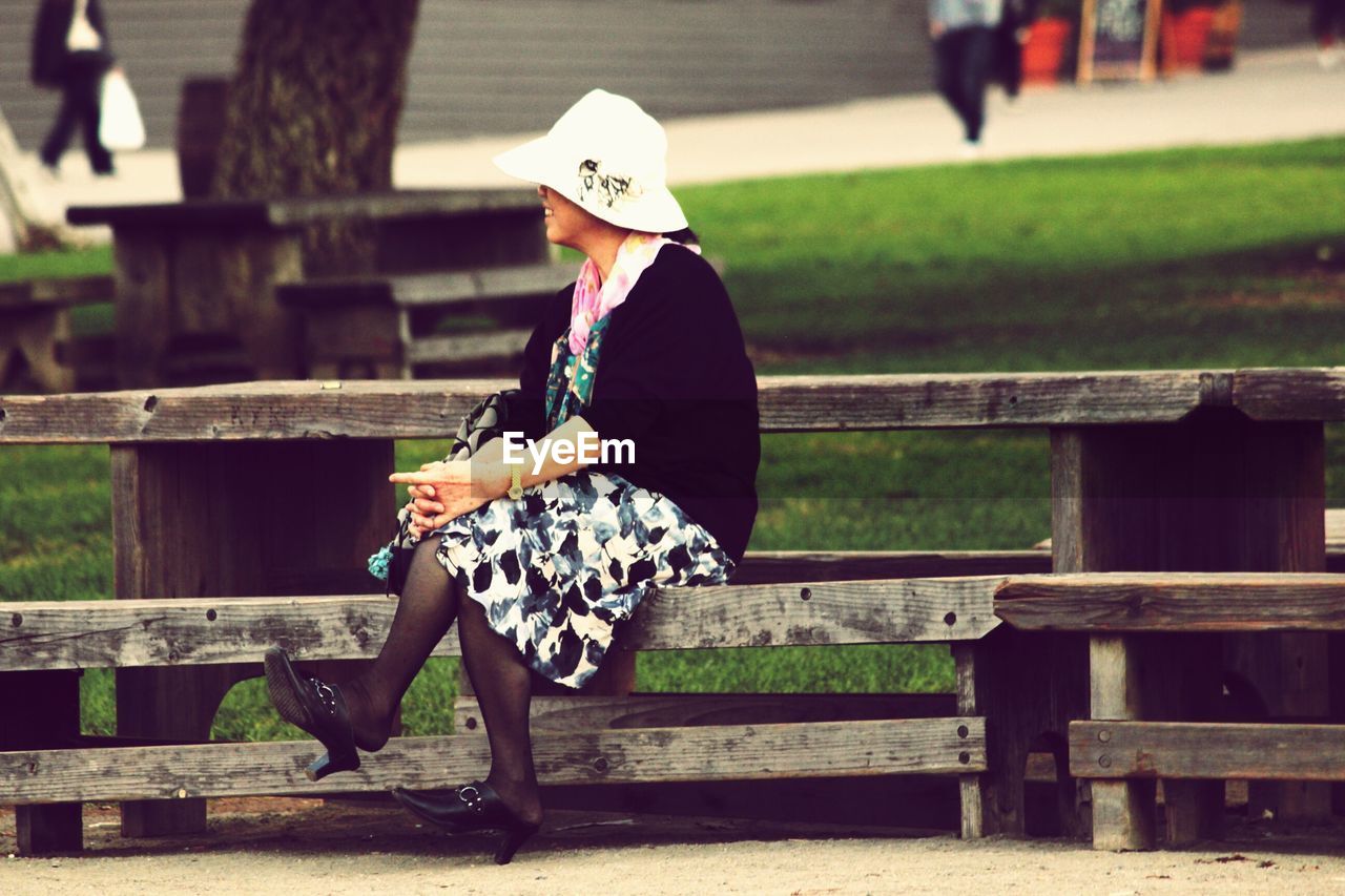 Full length of woman sitting on bench at park