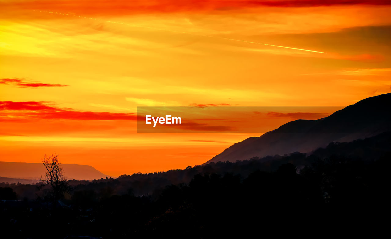 Scenic view of silhouette mountains against orange sky