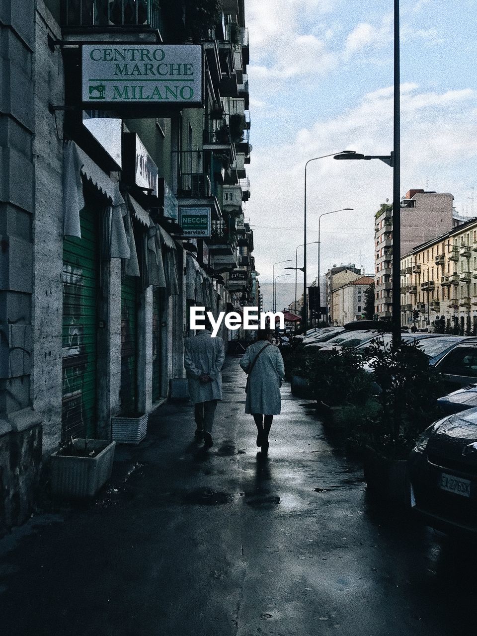 FULL LENGTH REAR VIEW OF MAN WALKING ON STREET IN RAINY SEASON