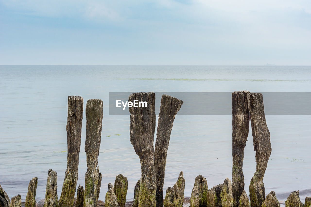 PANORAMIC VIEW OF WOODEN POST ON SEA AGAINST SKY