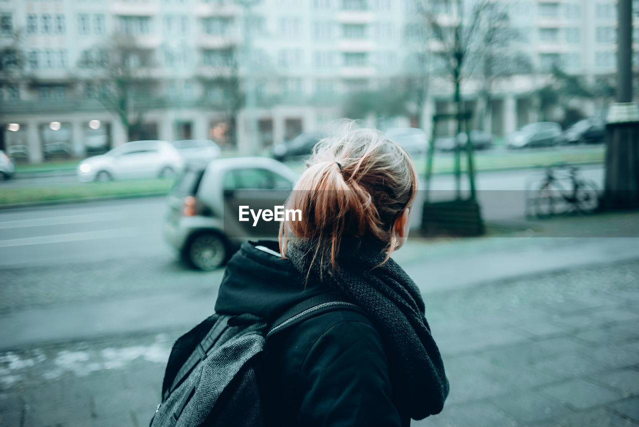 Side view of woman with backpack in city