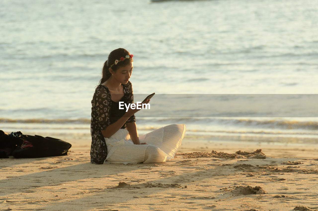 WOMAN SITTING ON BEACH WITH UMBRELLA