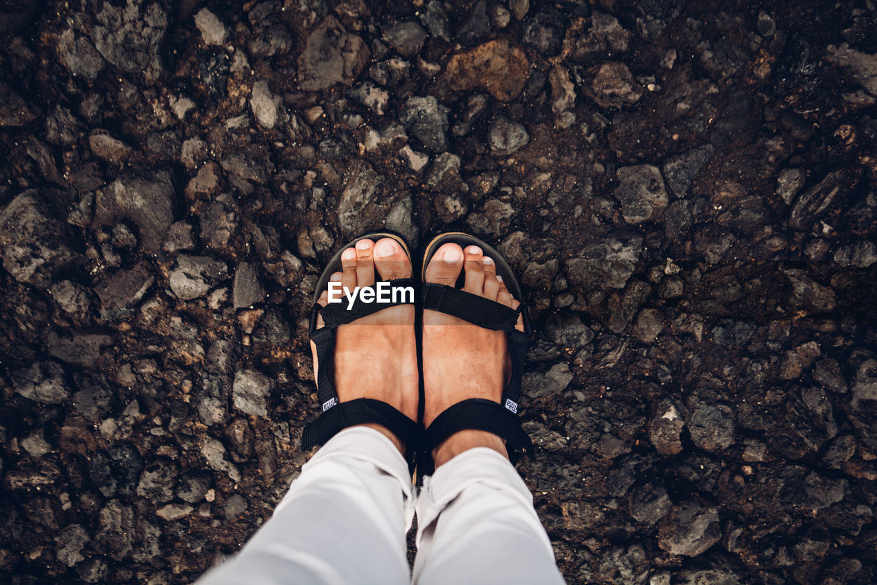 LOW SECTION VIEW OF WOMAN STANDING ON PEBBLES