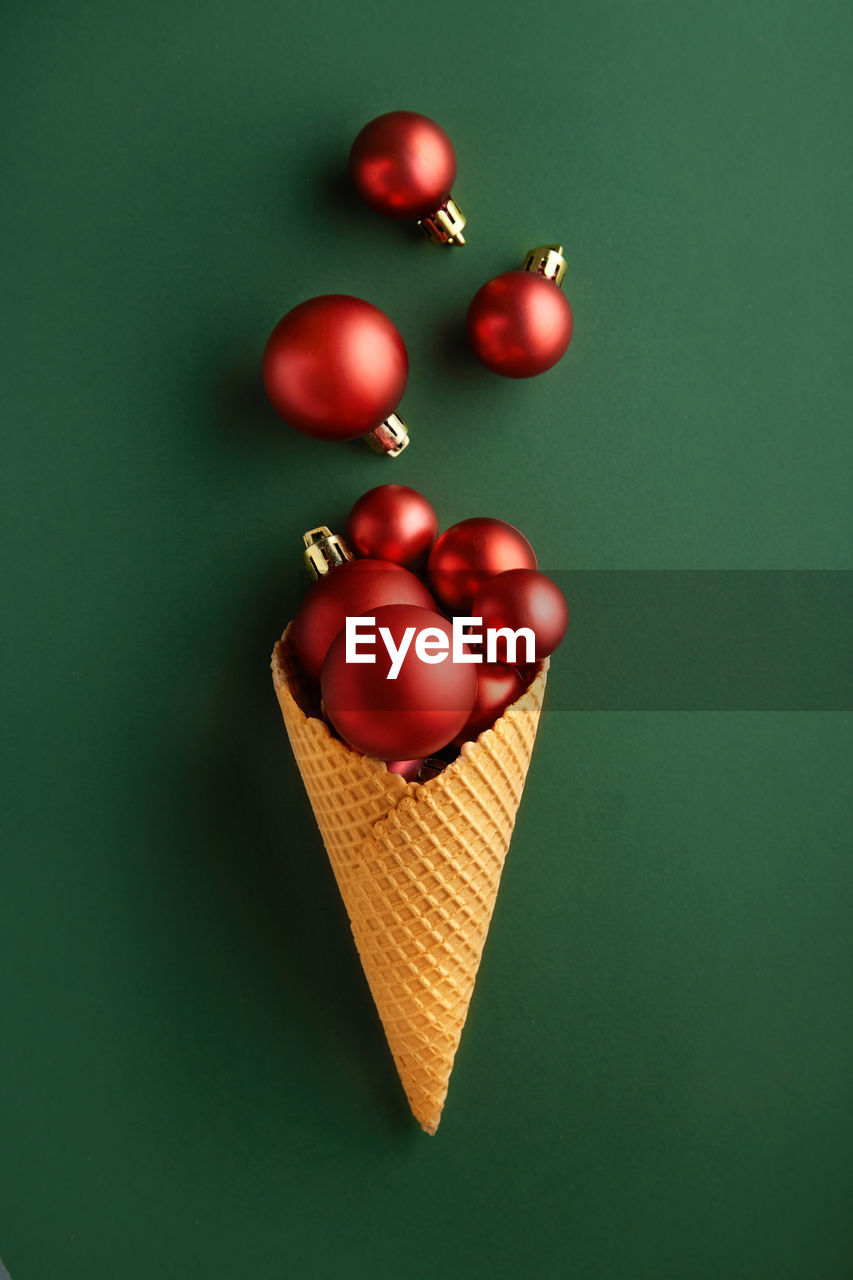 Directly above shot of ice cream cone with bauble over green background