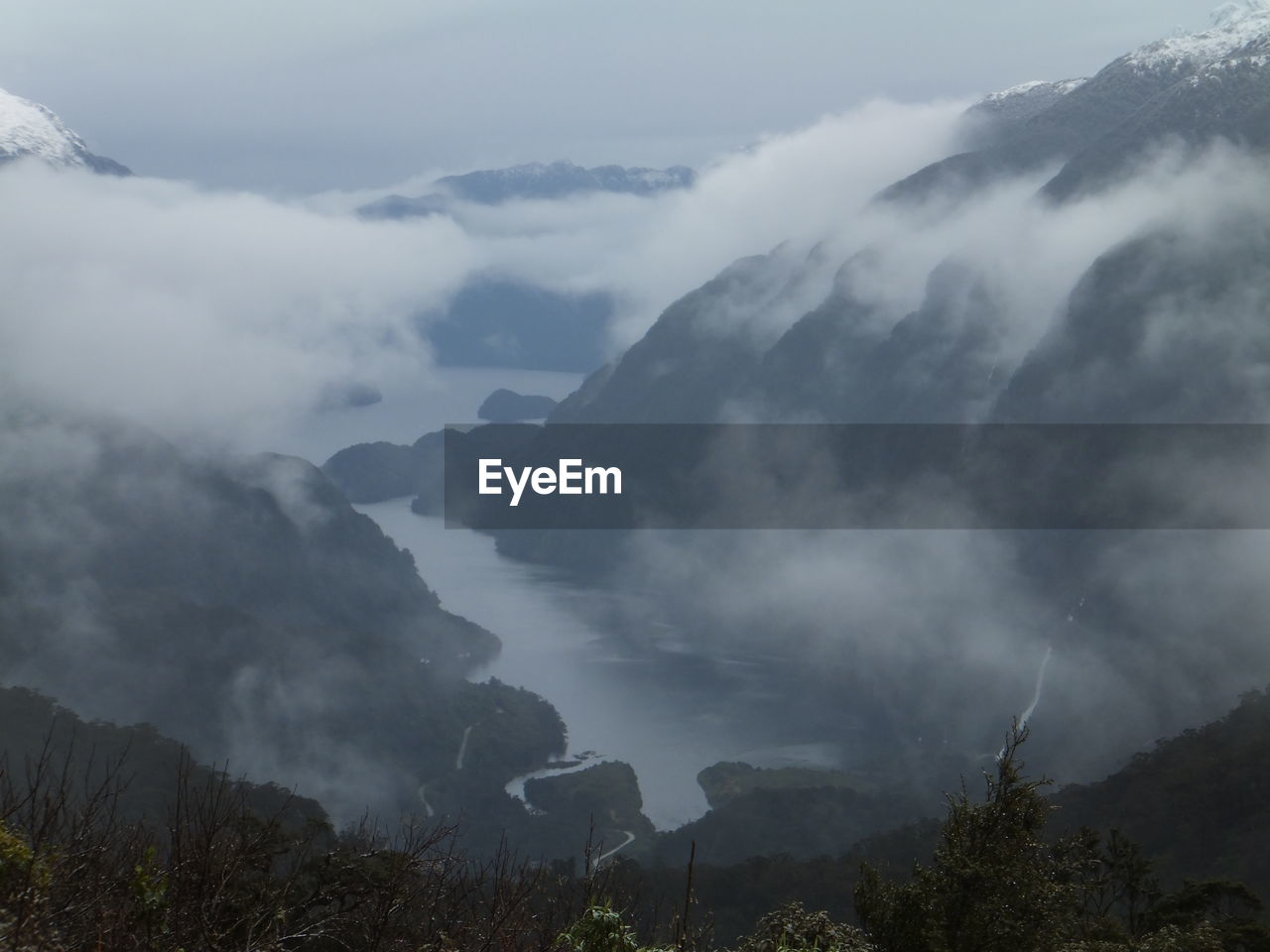 High angle view of river amidst mountains against clouds