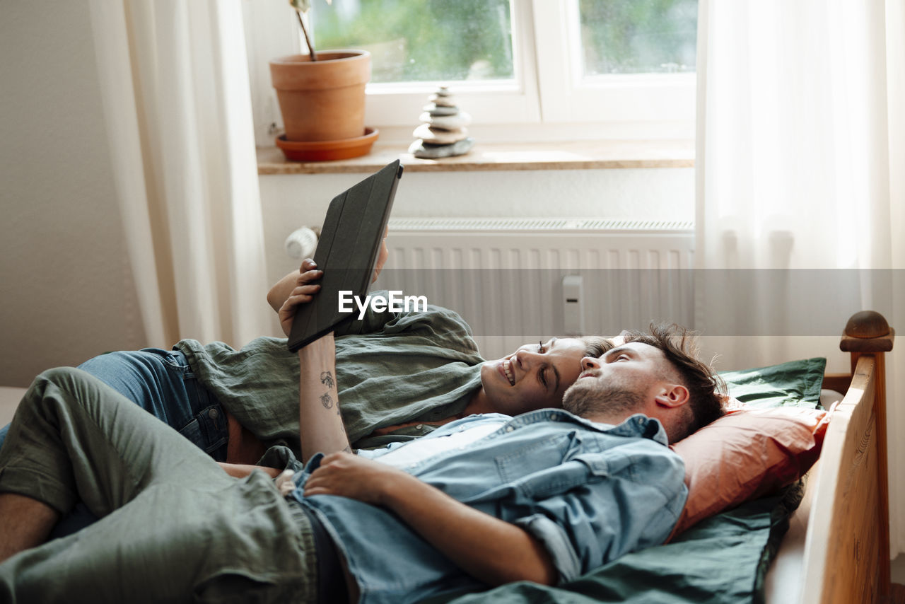 Couple using digital tablet at home