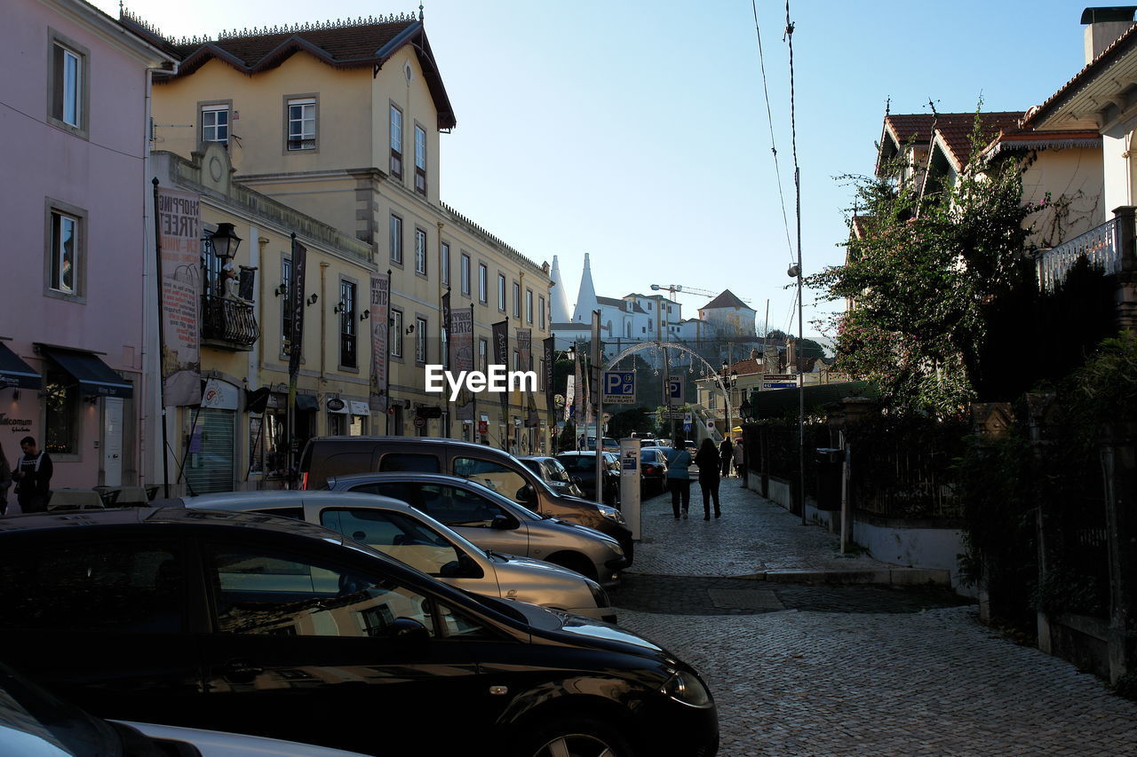 CARS ON STREET AMIDST BUILDINGS AGAINST SKY