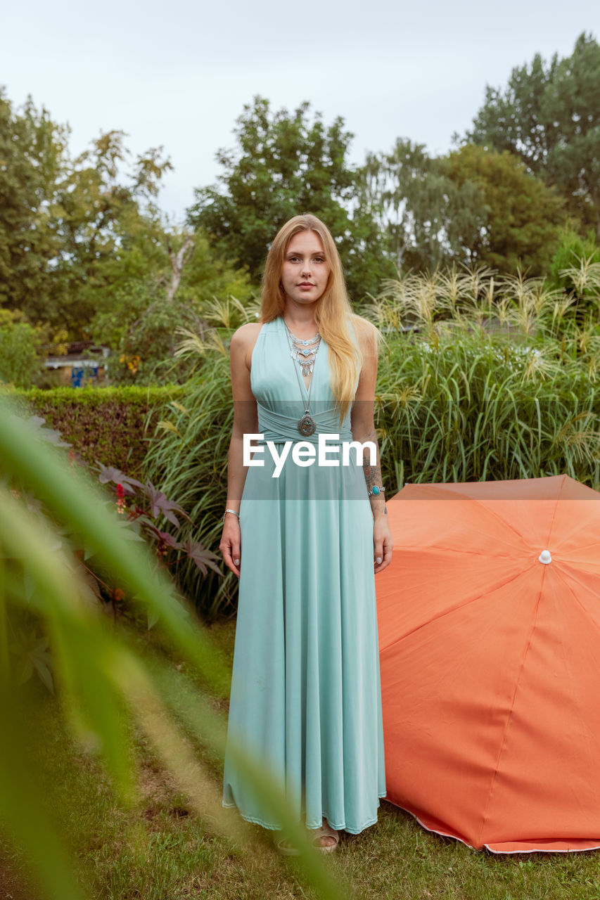 Portrait of young woman standing against plants