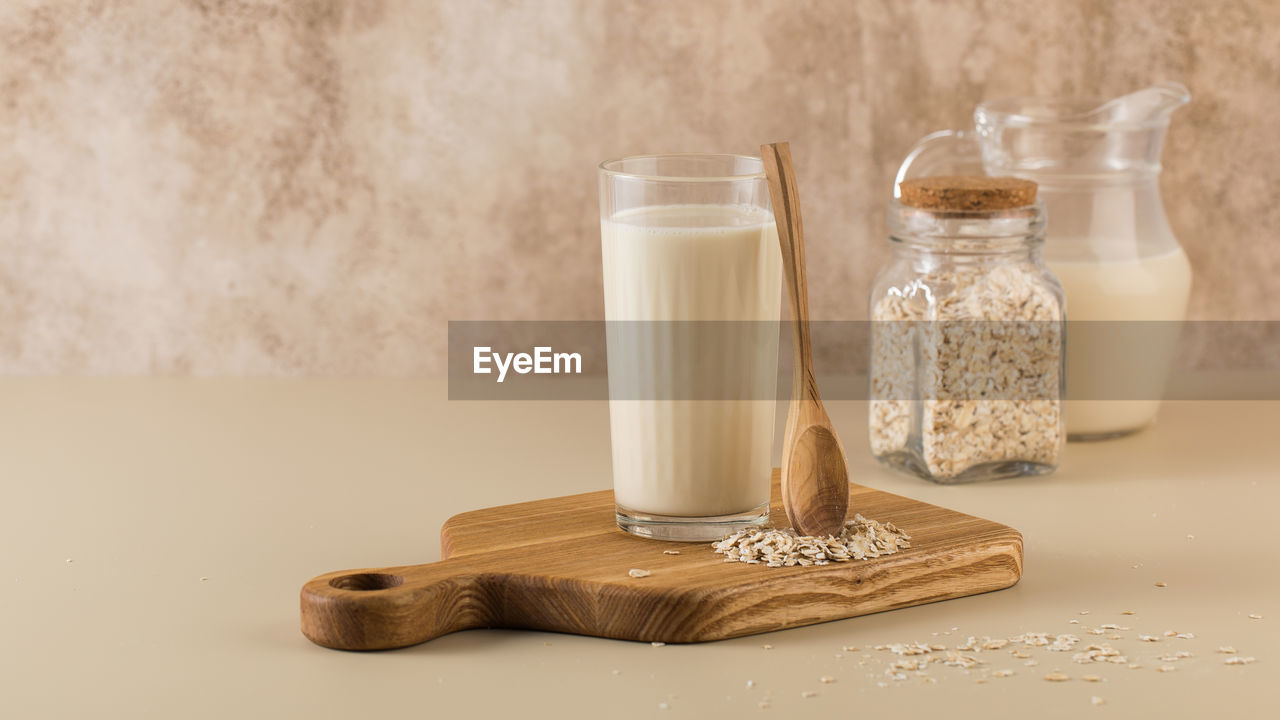 A glass of oat milk, a jug and oat flakes. the concept of alternative lactose-free dairy products. 