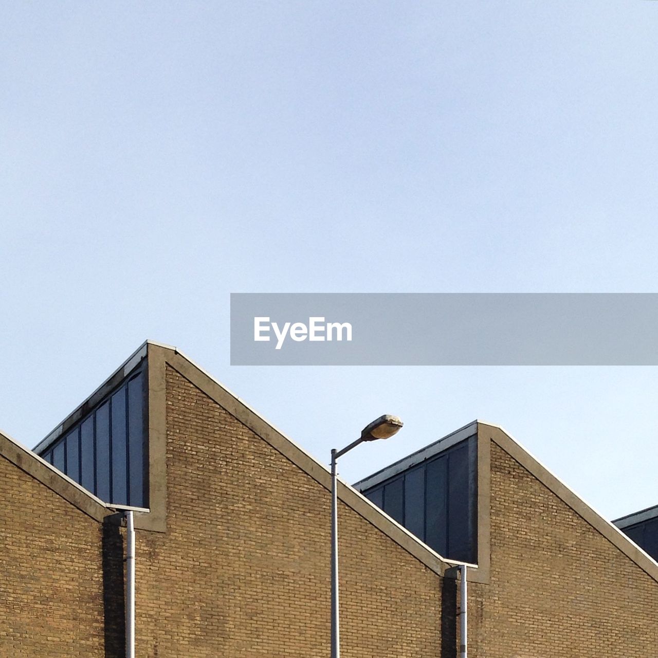 Low angle view of bird perching on roof