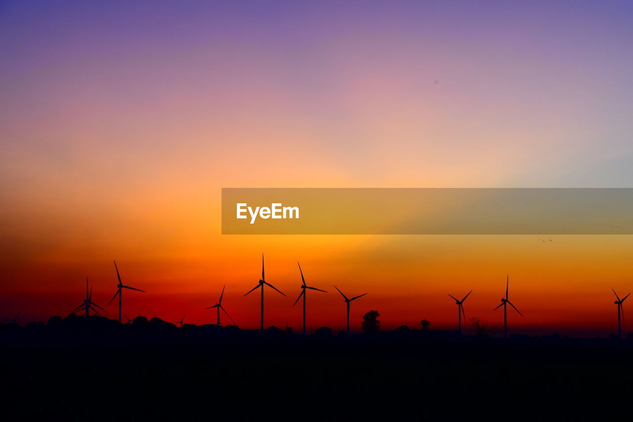 SILHOUETTE OF WIND TURBINES ON LAND DURING SUNSET