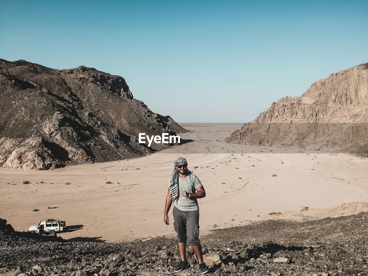 Full length of man standing on cliff against mountains at desert