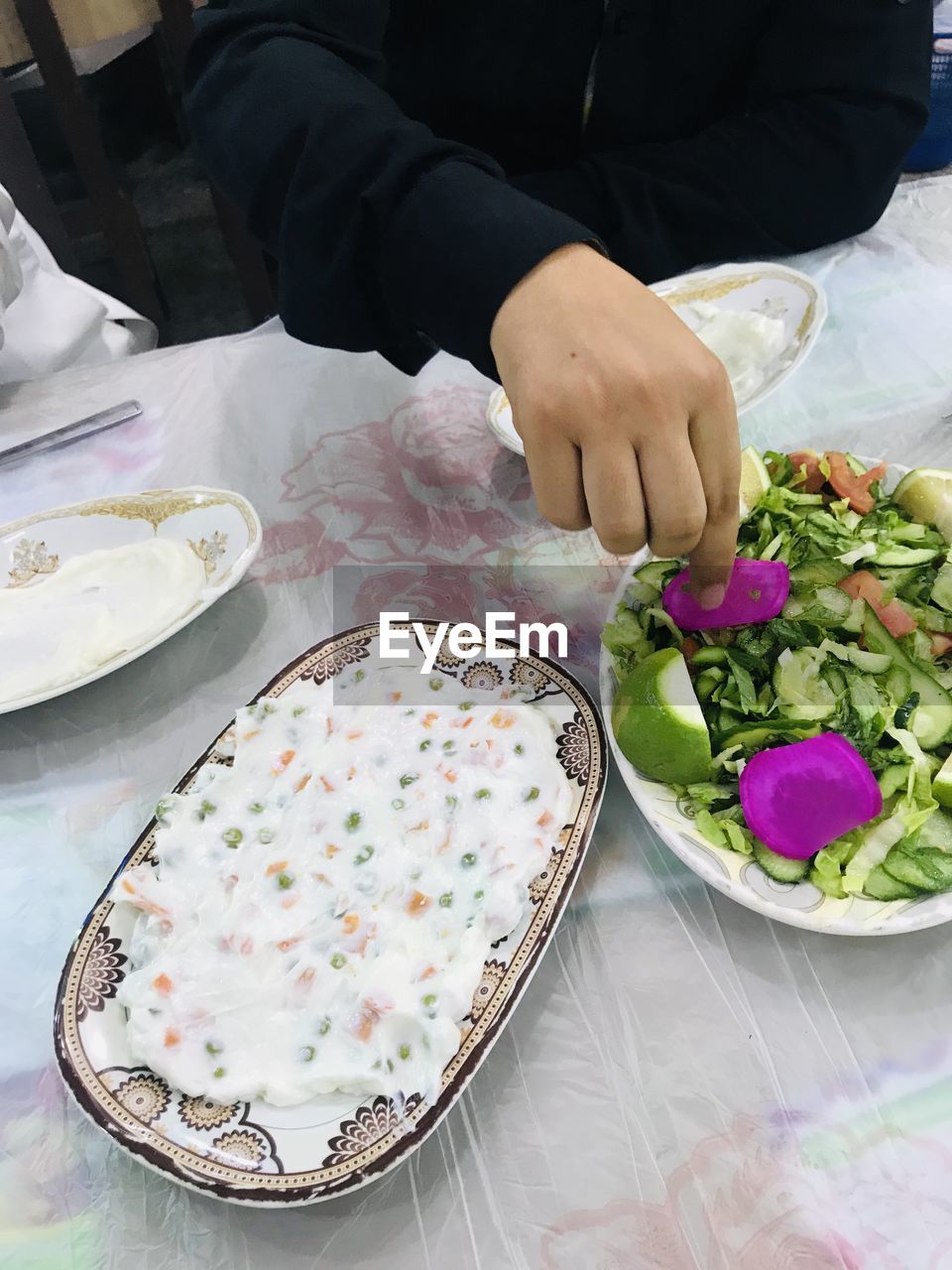 HIGH ANGLE VIEW OF PERSON HOLDING FOOD ON TABLE