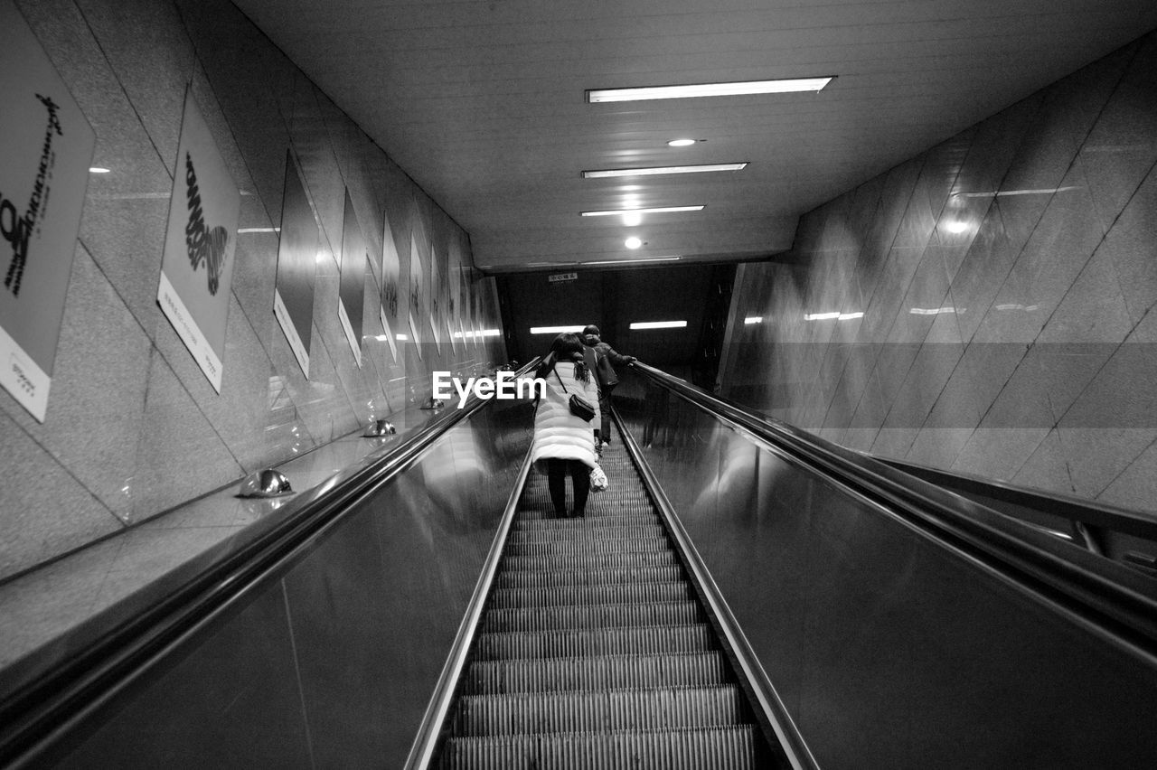 REAR VIEW OF MAN WALKING ON SUBWAY PLATFORM