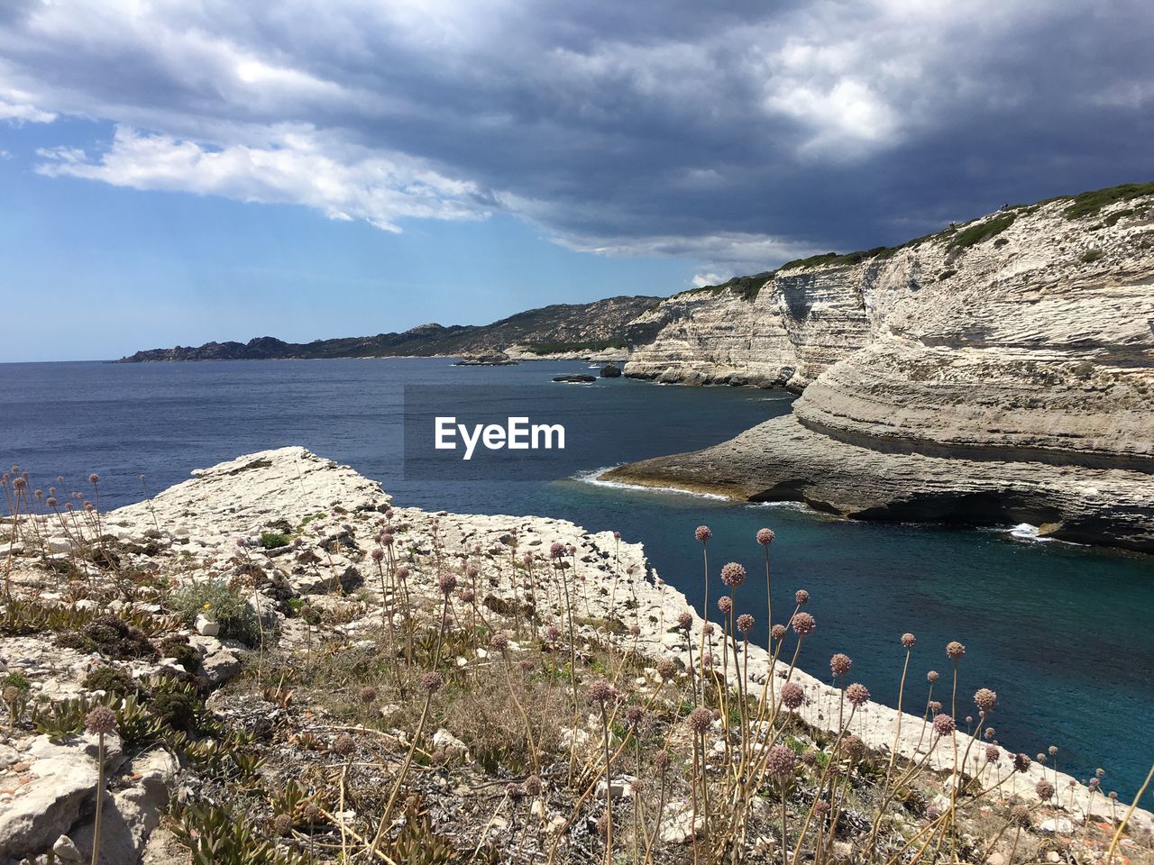 Scenic view of sea by mountains against sky